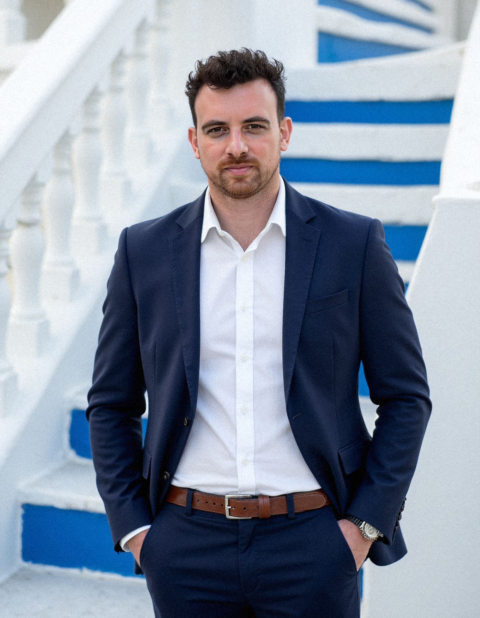 Henk Wolff, iGaming consultant, in a navy suit and open white shirt standing on white and blue painted steps.